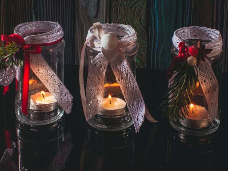 3 barattoli di vetro decorati con fiocchi e all'interno delle piccole candeline luminose