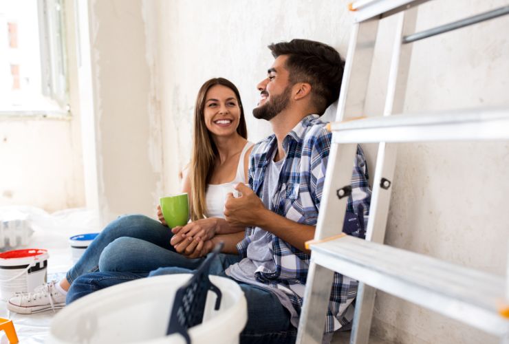 due giovani sorridenti mentre sono in casa da ristrutturare
