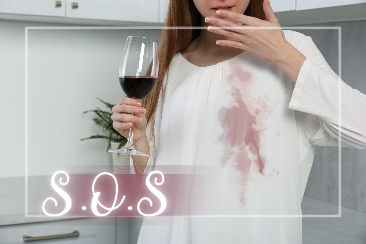 Donna con bicchiere di vino e macchia sulla camicia in cucina chiara