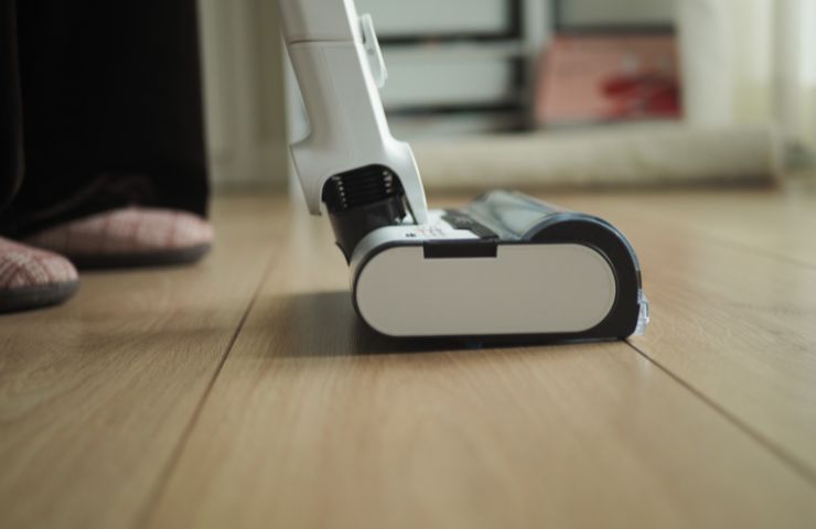 donna che usa aspirapolvere su pavimento