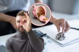 sfondo con una persona che fa conti, in primo piano un uomo che fa ok con la mano e un salvadanaio pieno di monete