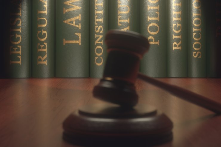 dei libri di legge sullo sfondo ed in primo piano un martello da giudice