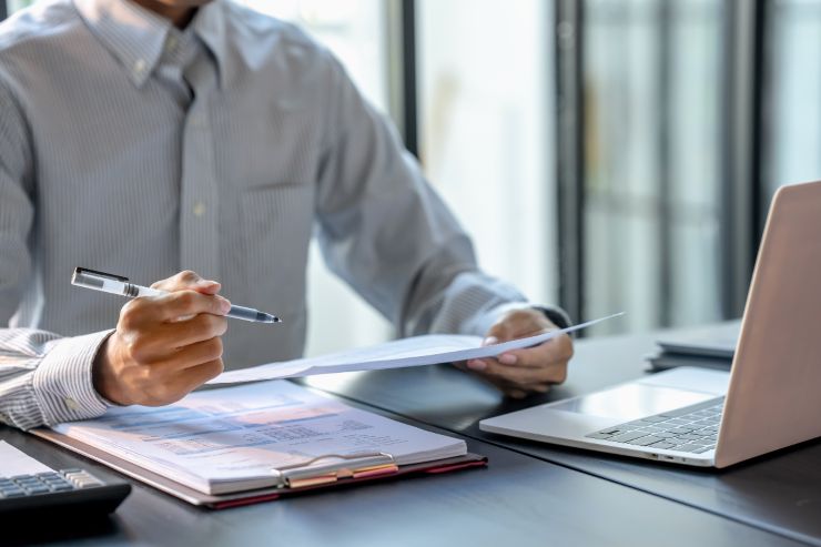 Un amministratore seduto alla scrivania con dei documenti ed un computer