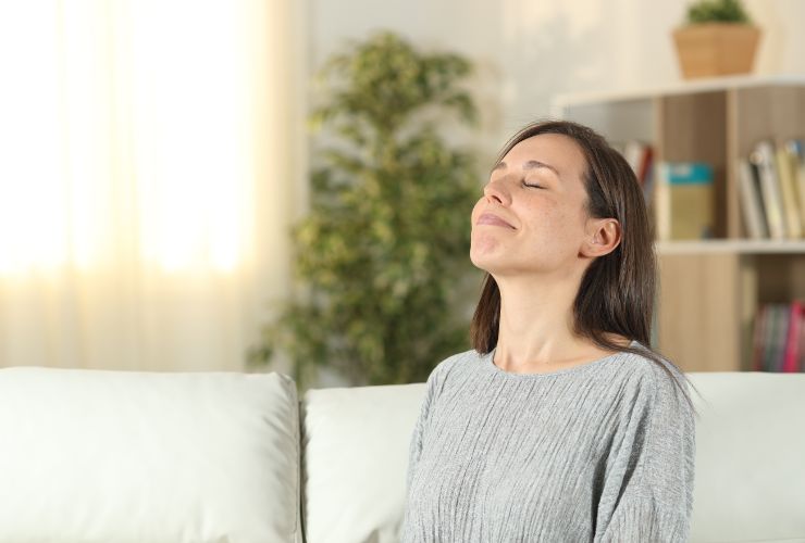 donna sorridente seduta sul divano che si gode l'aria di casa