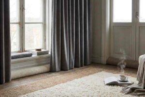 stanza con finastra con tenda scura e tappeto chiaro