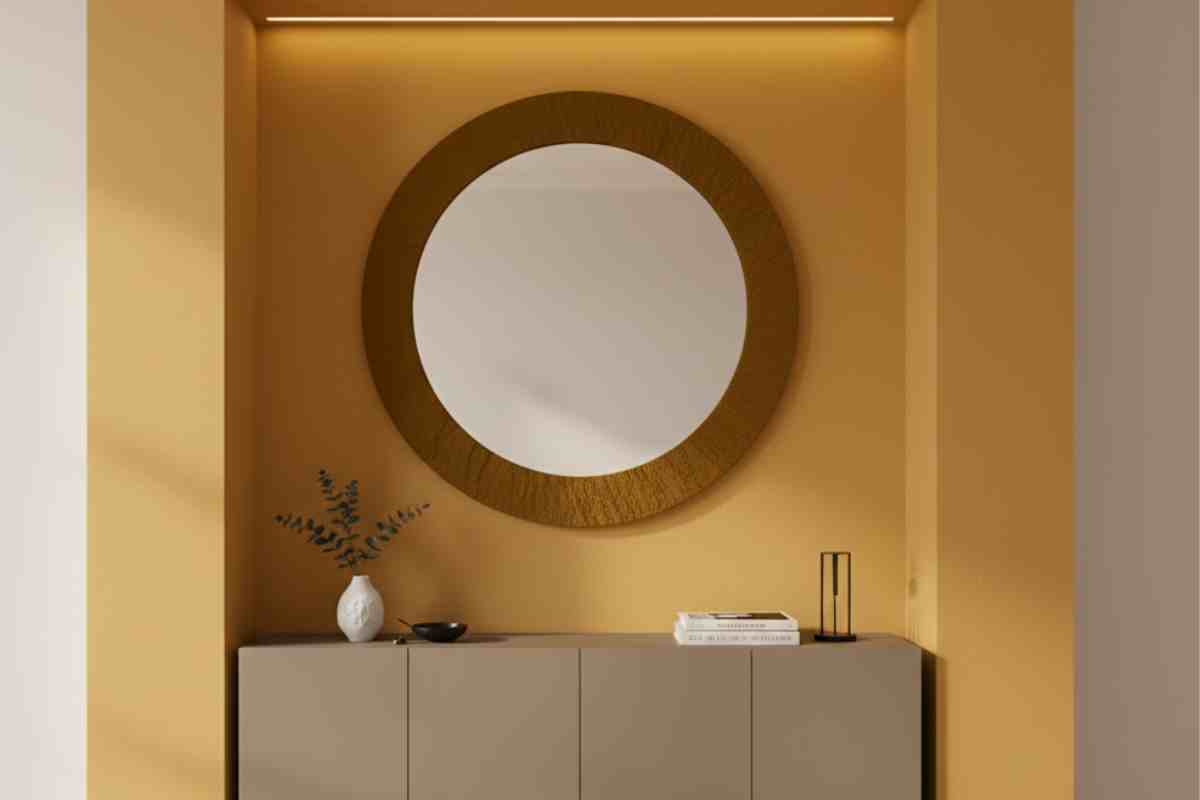 mobile tortora da ingresso su una parete giallo ocra con uno specchio tondo