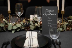 tavola elegante apparecchiata di nero, vetro e oro per capodanno