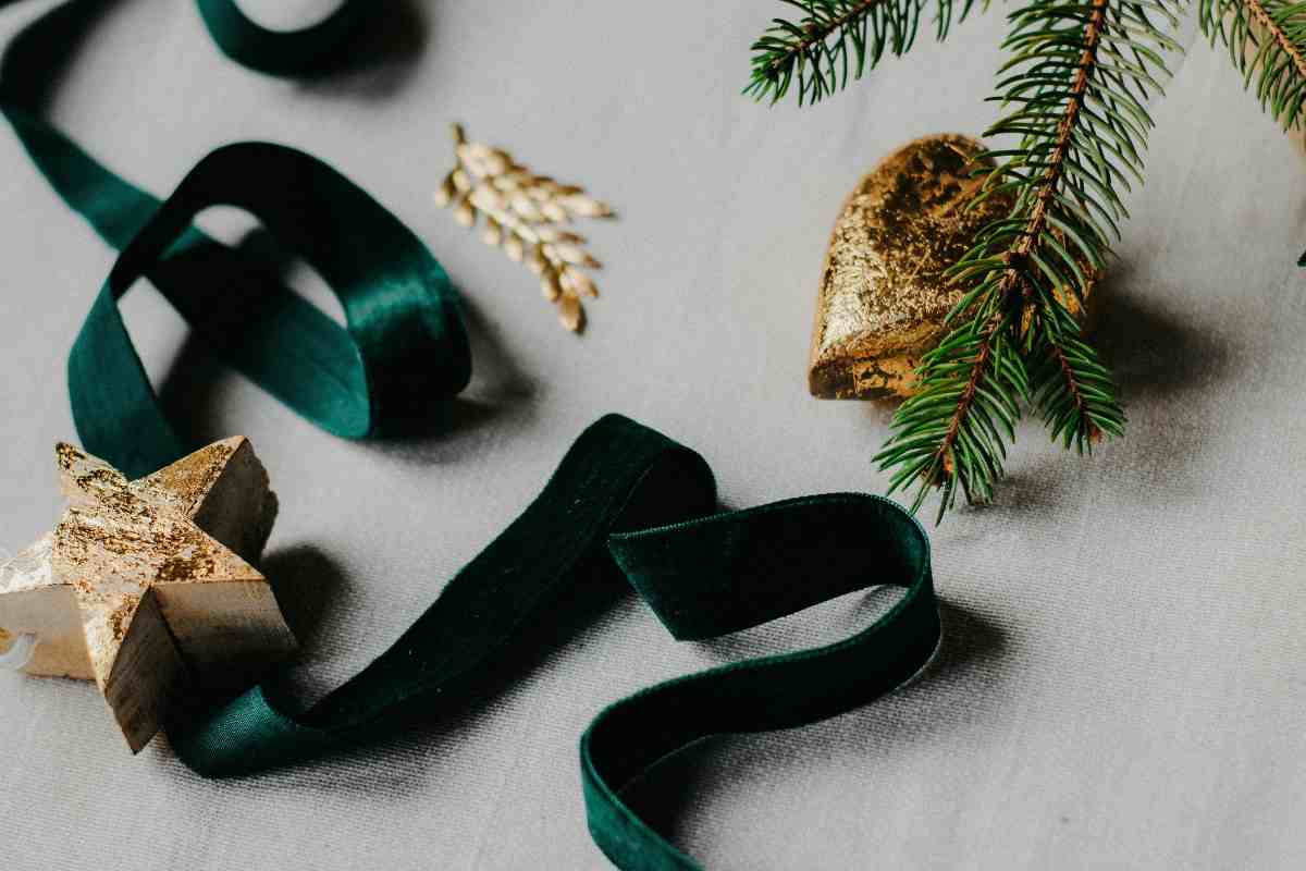 nastro di velluto verde, stelline e cuoricini di natale accanto ad un rametto di abete