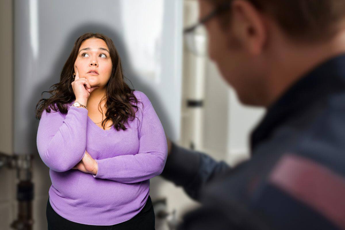 tecnico che controlla caldaia e donna che pensa