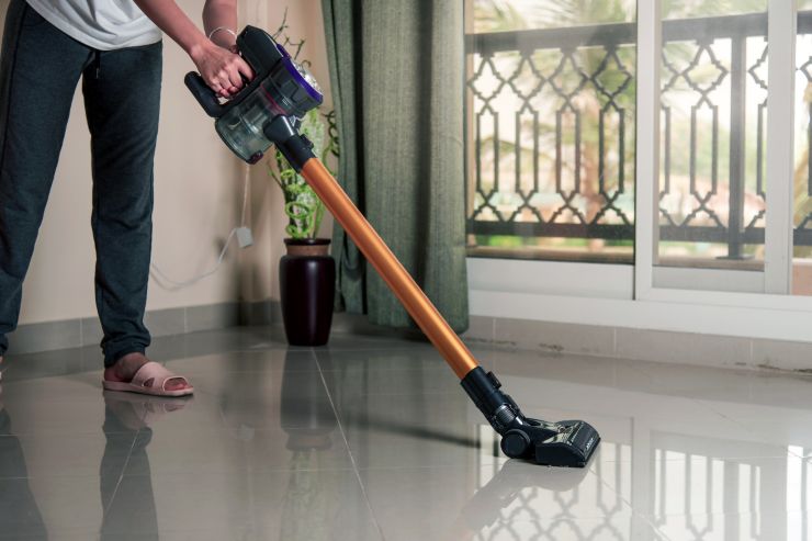 Una donna che usa la scopa elettrica in casa