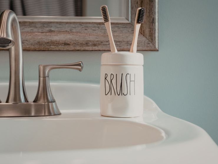 lavandino di un bagno sui cui è poggiato un bicchiere portaspazzolino