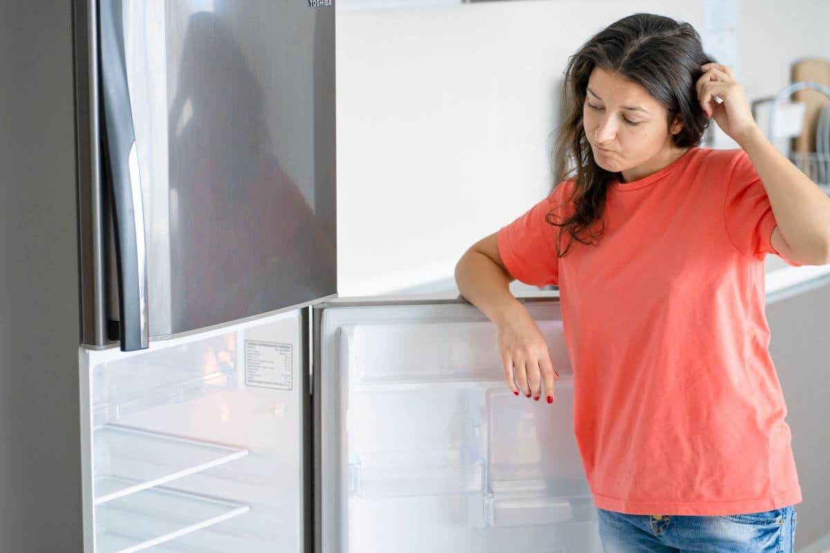 donna che guarda frigorifero vuoto
