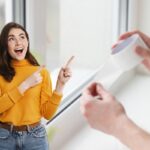 donna che esulta in primo piano e come sfondo una finestra di casa, su cui sta per essere applicata della carta protettiva