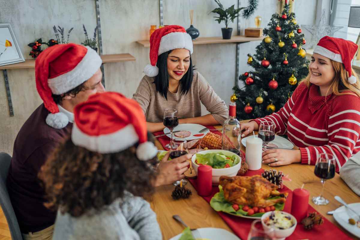 donna a tavola con cappello di babbo natale e cibo sul tavolo