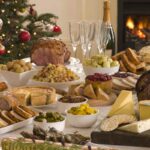 tavola di natale imbandita con tante pietanze con camino acceso e albero di natale