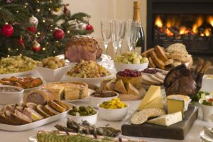 tavola di natale imbandita con tante pietanze con camino acceso e albero di natale