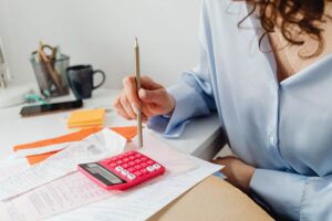 donna che fa conti con le bollette e calcolatrice rossa