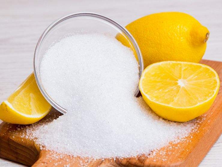 acido citrico e limoni sistemati su un tagliere in legno