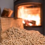 sfondo di una stufa accesa e in primo piano un cumulo di pellet