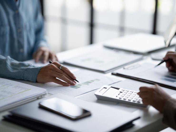 persone sedute ad una scrivania che controllano carte e fanno conti