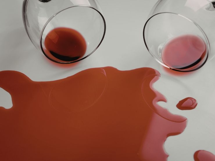 due calici di vino rosso rovesciati su una tovaglia chiara