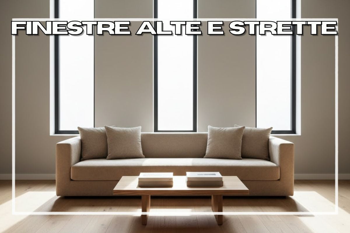 Divano chiaro con tavolino e tre finestre strette alle spalle