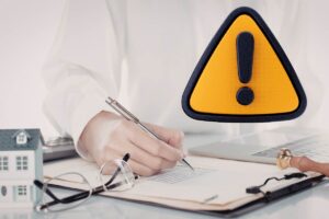 mano che firma documenti con casa vicino e simbolo attenzione