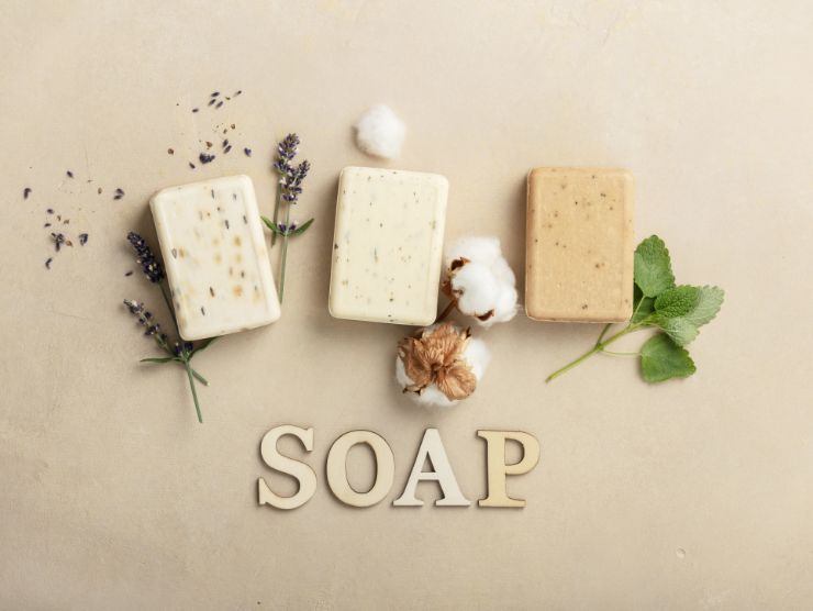 3 saponette naturali poggiate su una superficie e scritta sapone in inglese