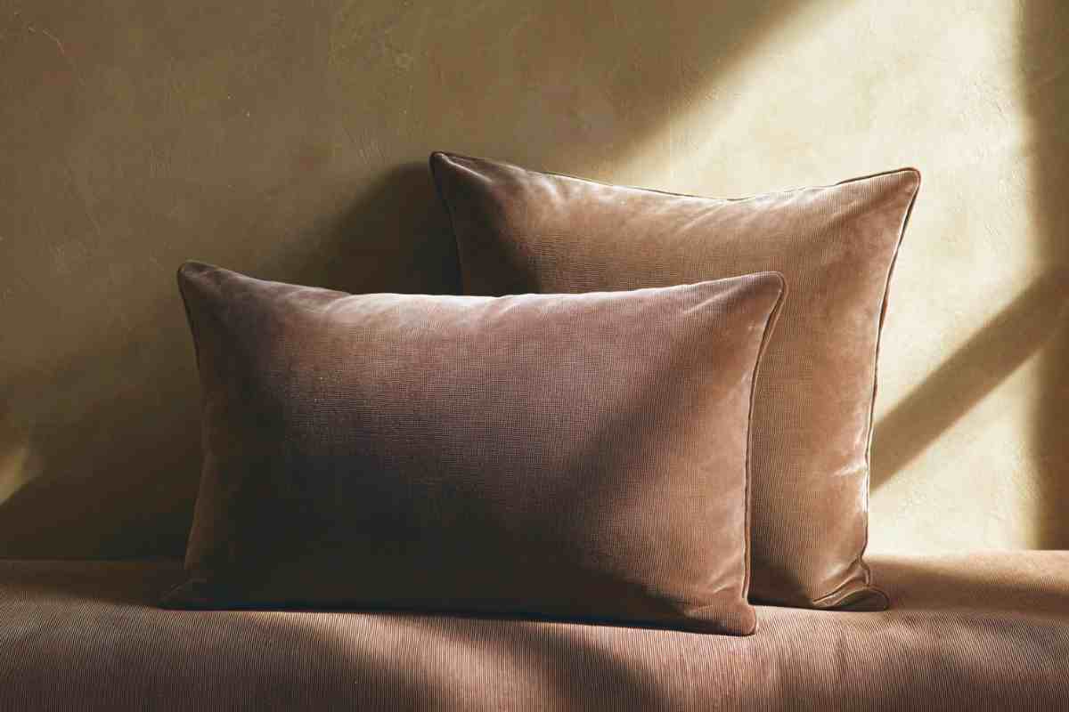 cuscini di varie misure in velluto marrone su parete color sabbia