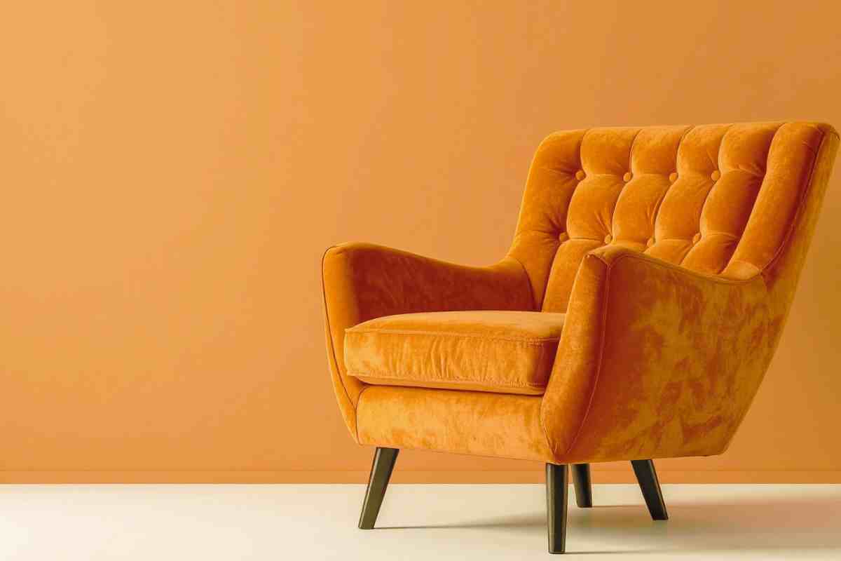 poltrona sui toni dell'arancione in velluto contro parete dello stesso colore