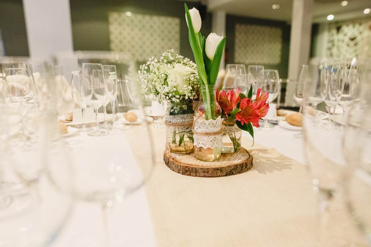 bicchieri sul tavolo con una bottiglia con fiori al centro