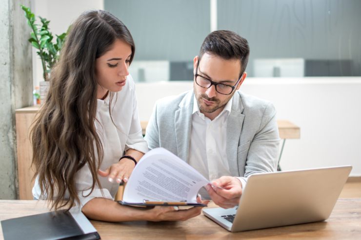 Due persone che controllano e consultano dei documenti 