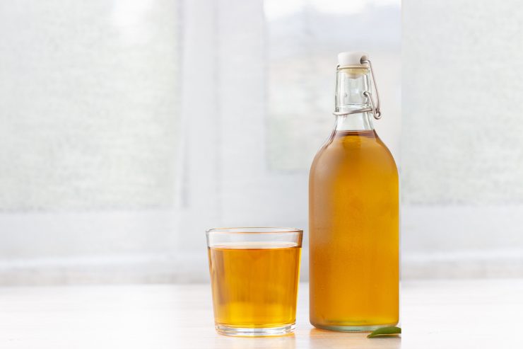 Una bottiglia di aceto bianco messo dentro un bicchiere