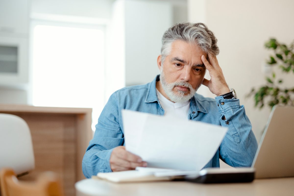 Un uomo che osserva la bolletta della luce ed ha uno sguardo preoccupato