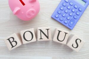 Un tavolo con sopra la scritta bonus, un salvadanaio e una calcolatrice