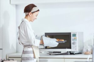 Una donna che mette del cibo da cuocere nel microonde