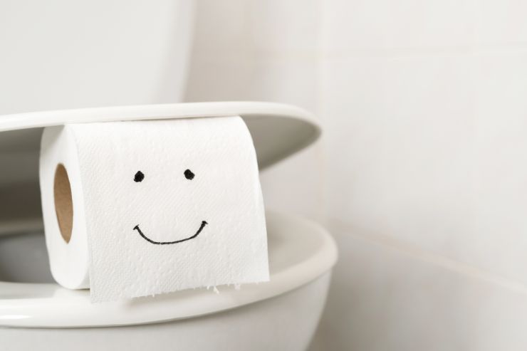 Un gabinetto con sopra un rotolo di carta igienica con sopra disegnata una faccia che sorride