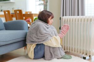 Una donna che sente freddo in casa e si mette vicino al termosifone