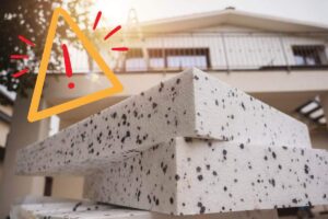 Il materiale del cappotto termico in primo piano e un segnale di pericolo in alto a sinistra