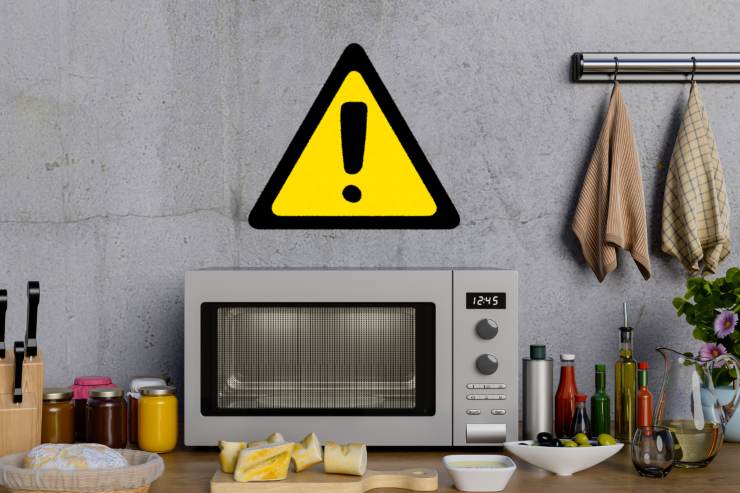 Un microonde su un tavolo con sopra un segnale di pericolo