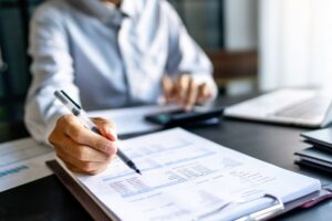 Un amministratore seduto alla scrivania mentre fa calcoli e compila documenti