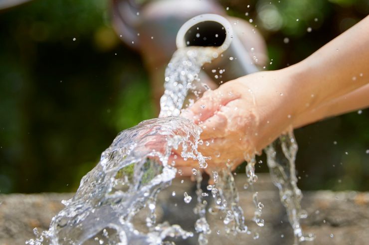 Dell'acqua che esce da un tubo e bagnano delle mani