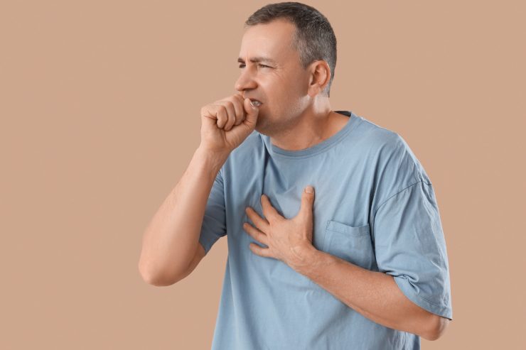 Una persona che si tocca il petto e tossisce