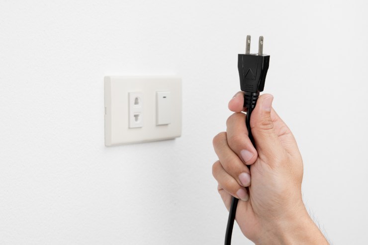 Un uomo che ha appena staccato una presa elettrica dalla corrente