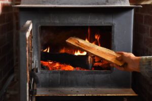 Un uomo che mette della legna nella stufa