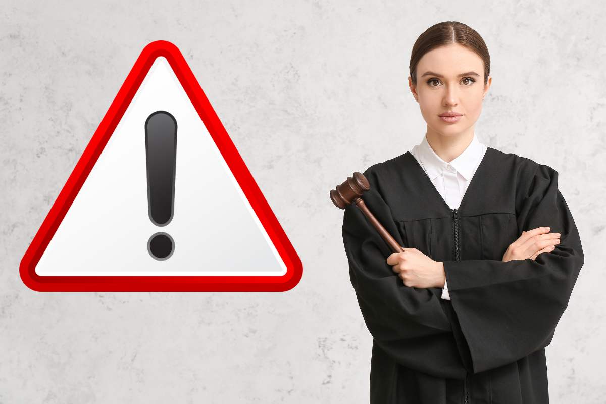 giudice con toga e martello e simbolo attenzione in rosso