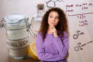 donna che pensa alle reazioni chimiche e sullo sfondo aceto e bicarbonato