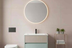 bagno rosa pallido con specchio retroilluminato e mobile bagno verde salvia
