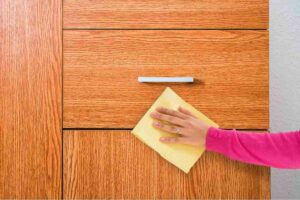 donna che pulisce mobile in legno
