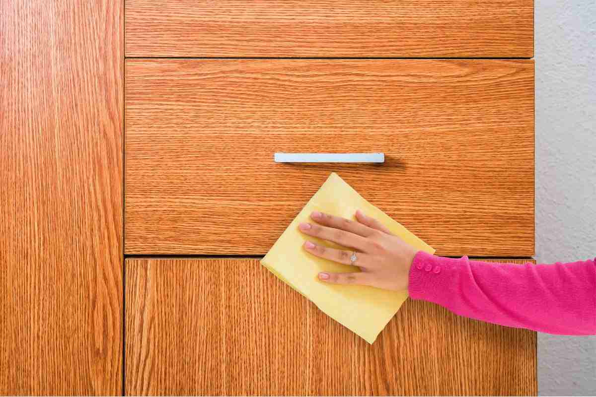 donna che pulisce mobile in legno